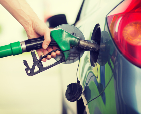 Person fueling their car using a green gas pump