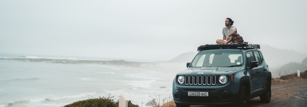 man-sitting-on-top-of-Jeep-SUV-by-ocean-RocketChip-Jeep-Performance-Chips
