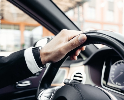 hand-on-steering-wheel-while-driving-vehicle-RocketChip-tips-for-better-mpg-on-your-daily-commute